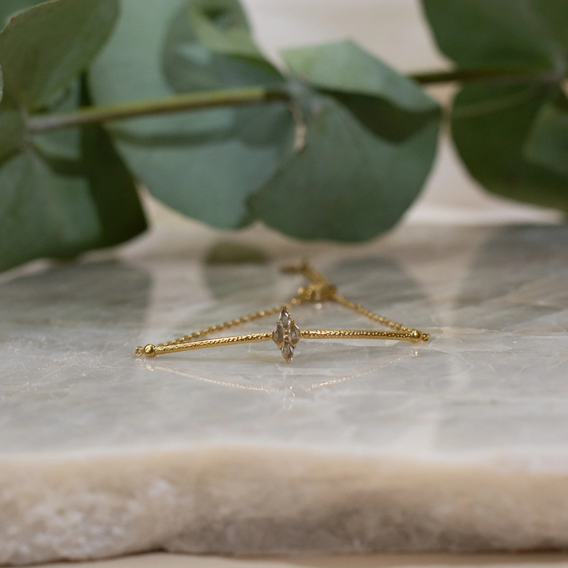 Jenny Bracelet Gold 3 gouden armband victoriaans design met elegante details klassieke uitstraling tijdloos sieraad voor dames gepresenteerd op marmeren achtergrond met bladeren
