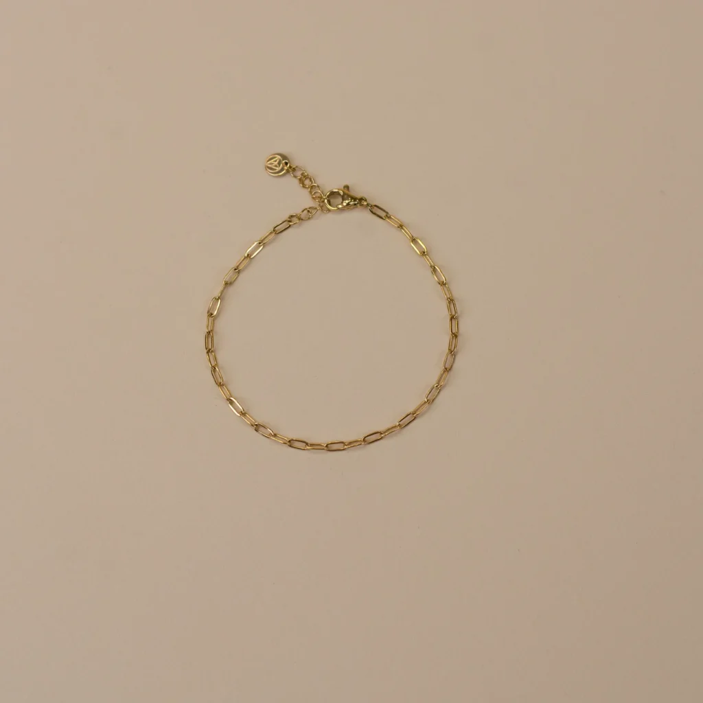 Tess Bracelet Gold 1 minimalistische gouden armband voor vrouwen, bovenaanzicht gefotografeerd op beige achtergrond, stijlvol sieraad uit de Sarae collectie
