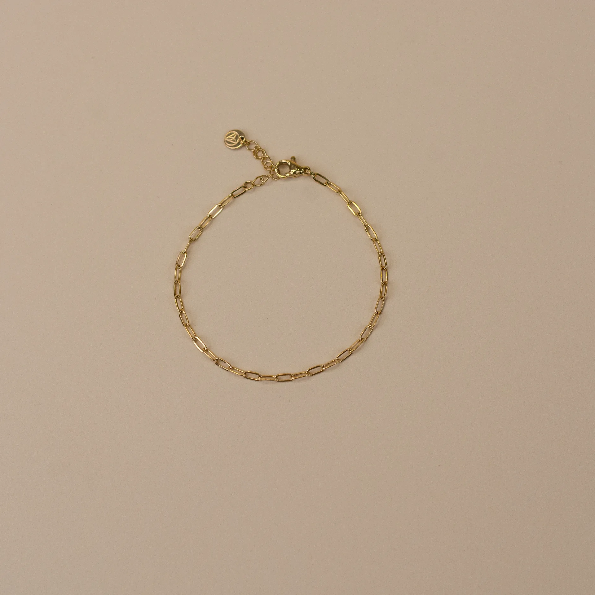 Tess Bracelet Gold 1 minimalistische gouden armband voor vrouwen, bovenaanzicht gefotografeerd op beige achtergrond, stijlvol sieraad uit de Sarae collectie